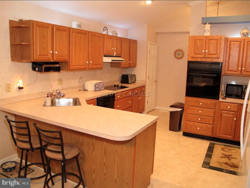 35 Falcon Bridge Road Berlin, MD 21811 - Photo 9 of 21 a kitchen with stainless steel appliances a stove a sink dishwasher and a refrigerator with wooden cabinets