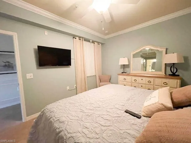 a bedroom with a bed a flat screen tv and a chandelier