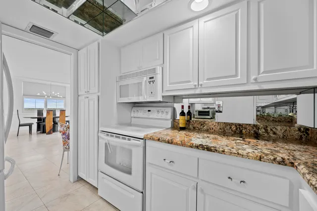 a kitchen with granite countertop white cabinets and stainless steel appliances