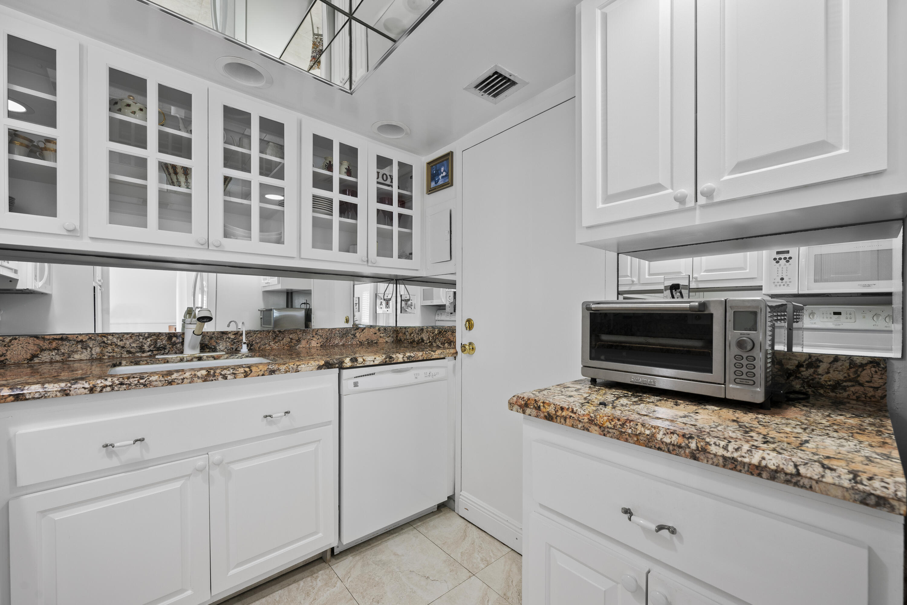 2600 North Flagler Drive, Unit 1007 West Palm Beach, FL 33407 - Photo 8 of 26 a kitchen with stainless steel appliances granite countertop a stove a sink and a white cabinets