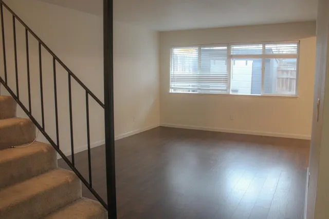 a view of an empty room with wooden floor and windows