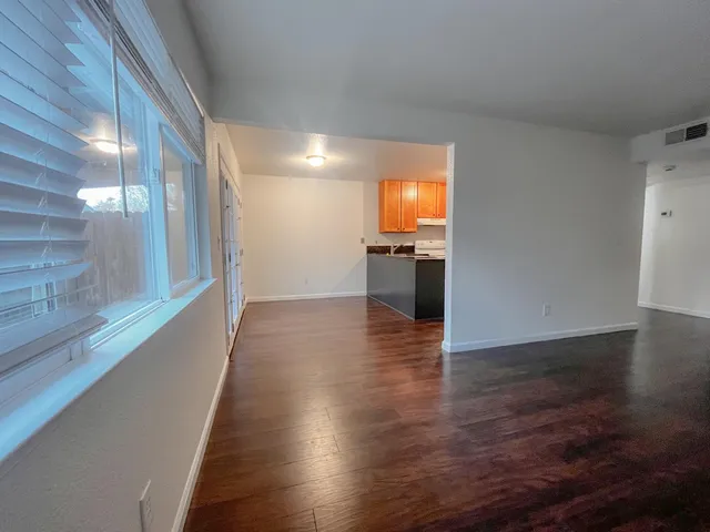 a view of a room with wooden floor and kitchen space