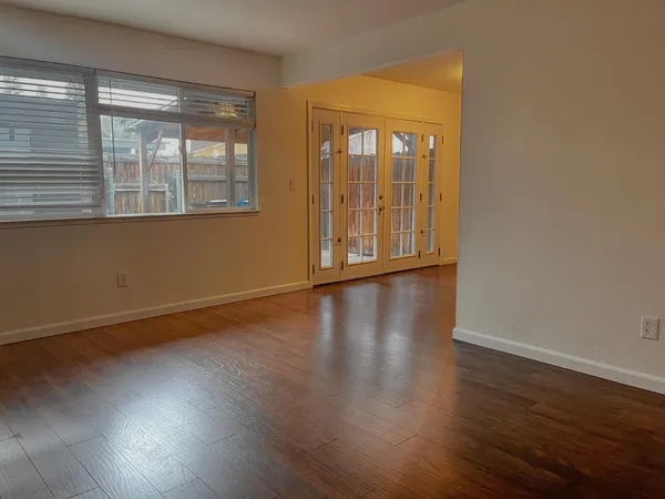 a view of an empty room with wooden floor and a window