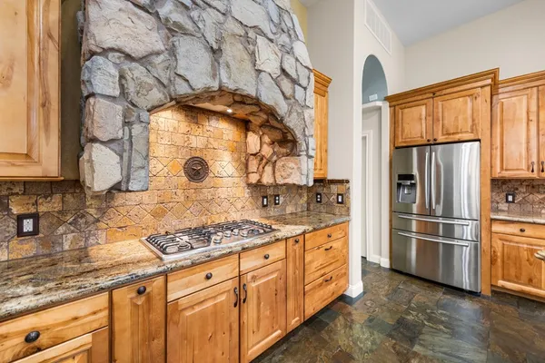 a kitchen with stainless steel appliances granite countertop a refrigerator a stove and a sink with wooden floor