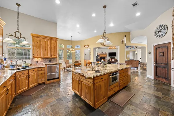 a large kitchen with stainless steel appliances granite countertop a stove and cabinets