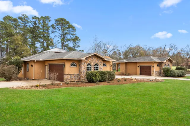 a front view of a house with a garden and trees