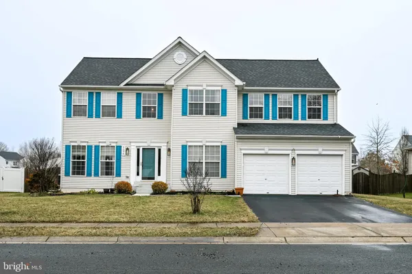 a view of a white house with a yard and large parking space