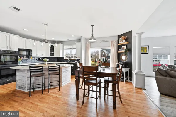 a kitchen with stainless steel appliances kitchen island granite countertop a stove a refrigerator a kitchen island a dining table and chairs with wooden floor