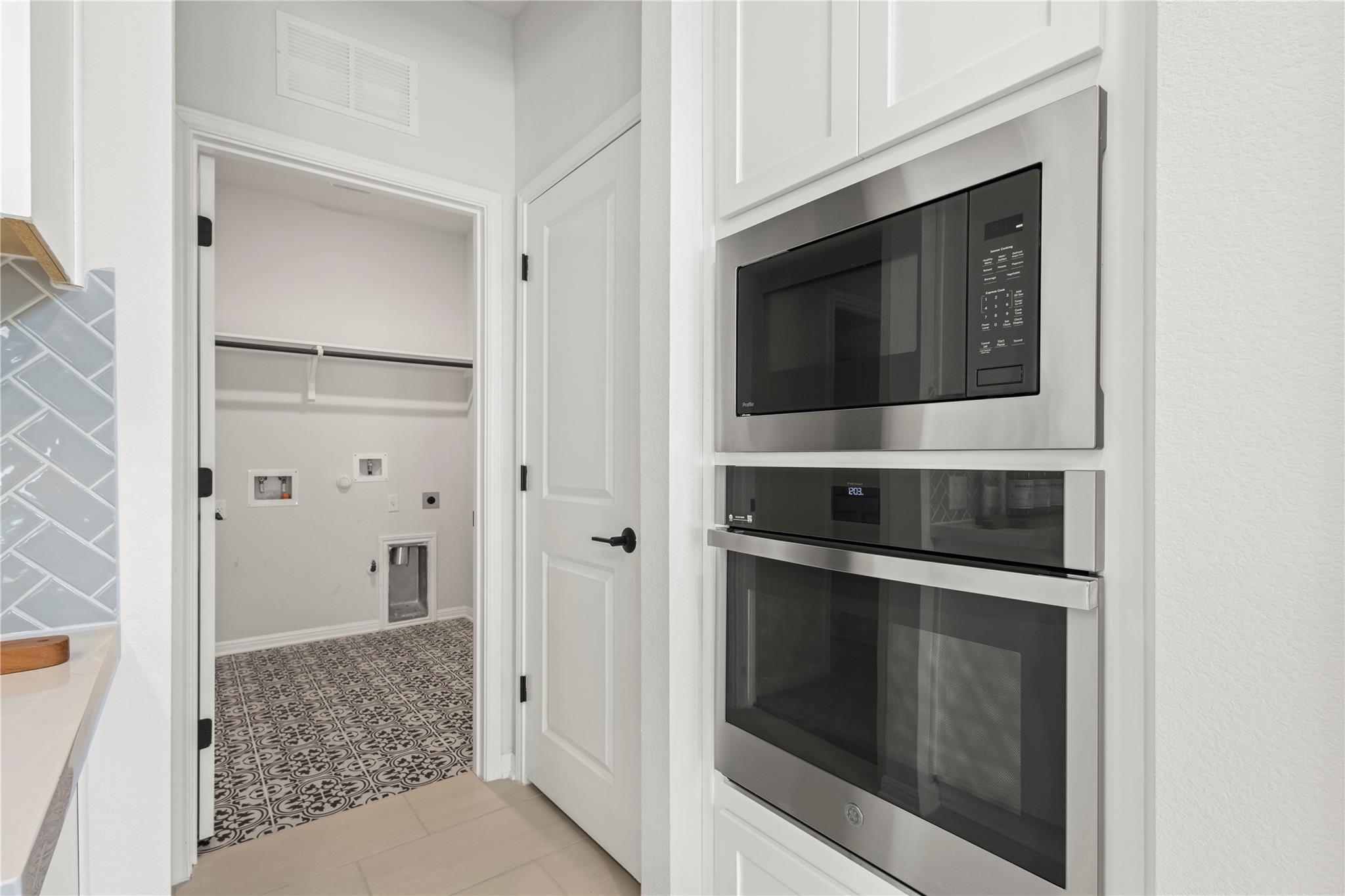 1128 Villa Rialto View Leander, TX 78641 - Photo 18 of 40 Seamlessly integrated appliances elevate this modern laundry area with elegant tile work and practical shelving.