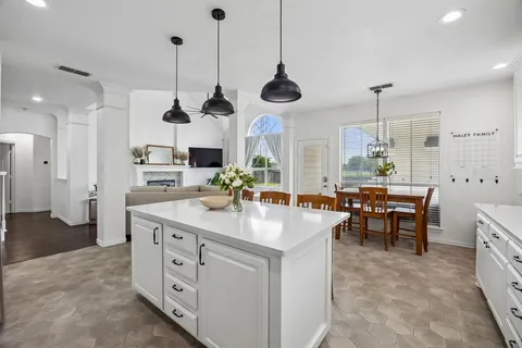 a kitchen with stainless steel appliances kitchen island granite countertop a stove a oven a dining table and chairs with wooden floor