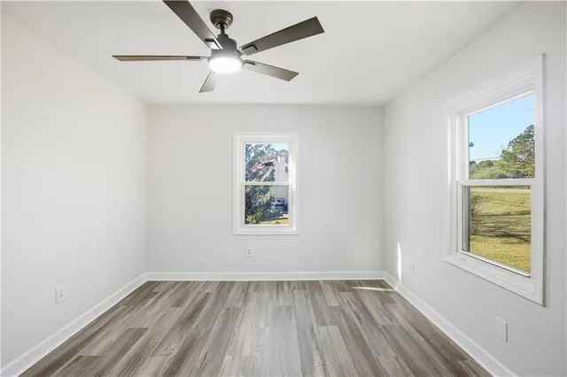 a view of an empty room with a window and wooden floor