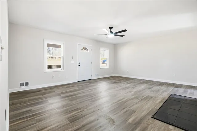 an empty room with wooden floor and windows