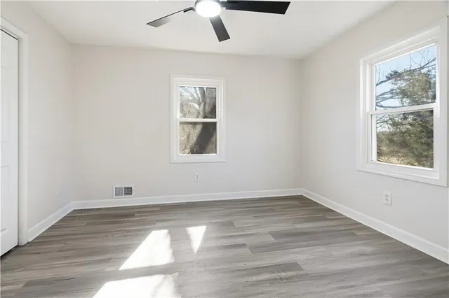 a view of empty room with wooden floor and fan