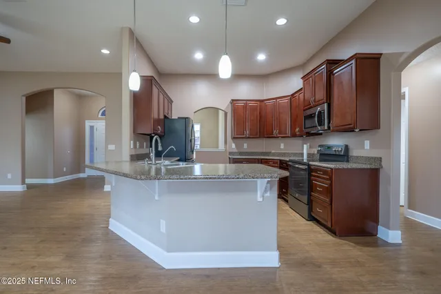 a kitchen with stainless steel appliances granite countertop a stove a sink a refrigerator and a microwave