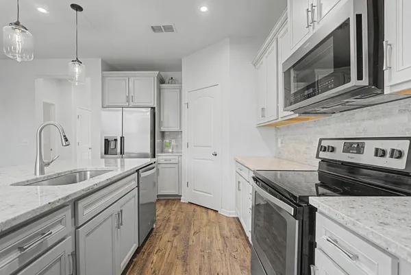 a kitchen with appliances a sink a stove a microwave and cabinets