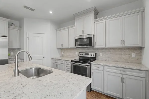 a kitchen with stainless steel appliances granite countertop a stove a sink and a microwave
