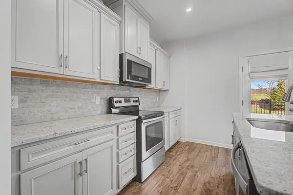 a large kitchen with stainless steel appliances kitchen island granite countertop a stove a sink a center island a refrigerator and a wooden floor