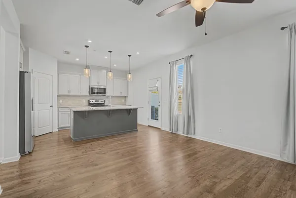 a kitchen with stainless steel appliances kitchen island granite countertop a sink a stove a dining table and chairs