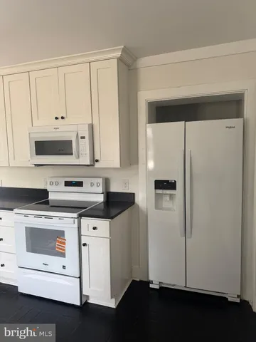 a kitchen with stainless steel appliances a refrigerator a stove and white cabinets