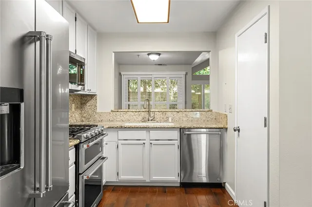 a kitchen with stainless steel appliances granite countertop a refrigerator and a sink