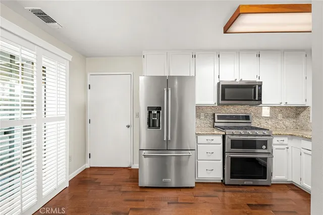 a kitchen with a refrigerator stove and wooden floor