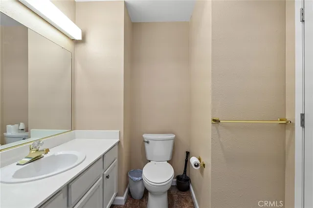 a bathroom with a granite countertop toilet a sink and a mirror