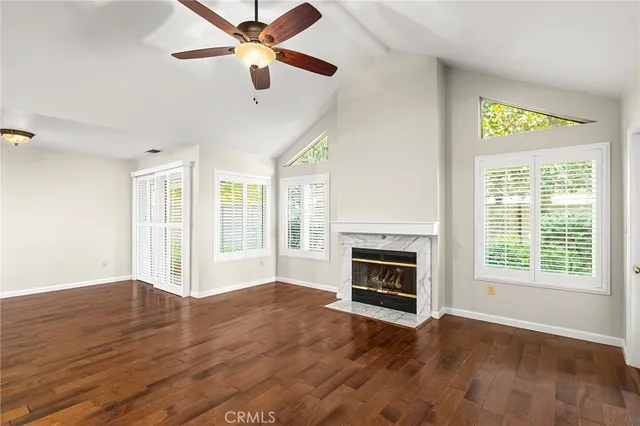a view of an empty room with wooden floor fireplace and a window