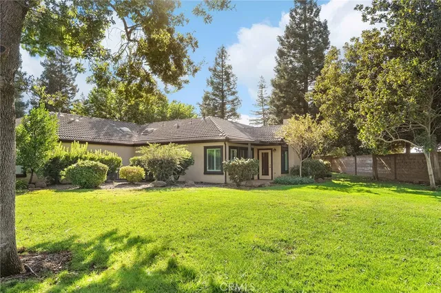 a view of a house with a yard and large trees