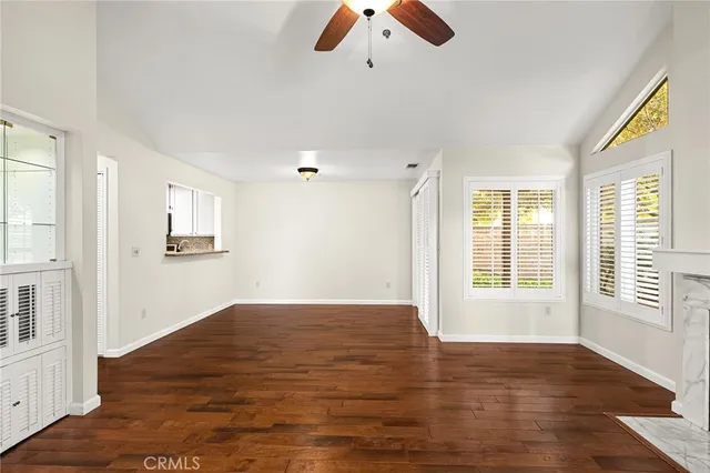 a view of an empty room with window and wooden floor