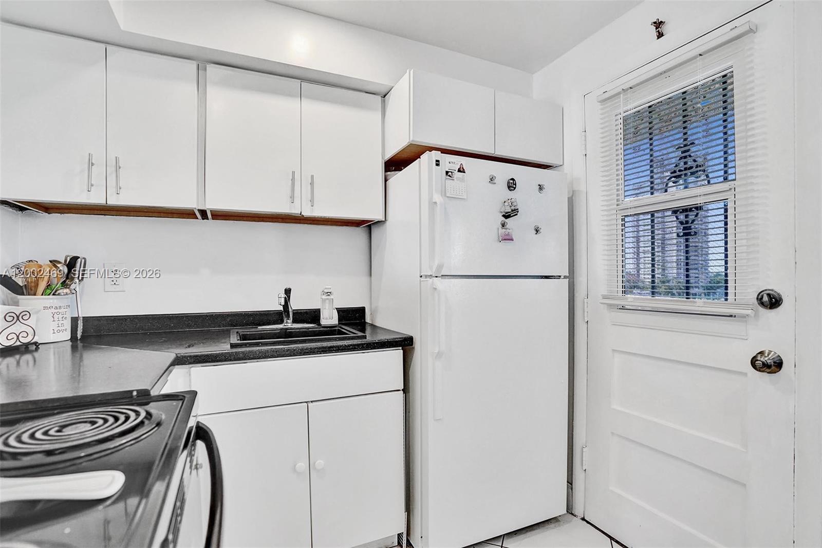2999 Point E Drive, Unit C511 Aventura, FL 33160 - Photo 11 of 33 a white kitchen with granite countertop a refrigerator a stove a sink and cabinets