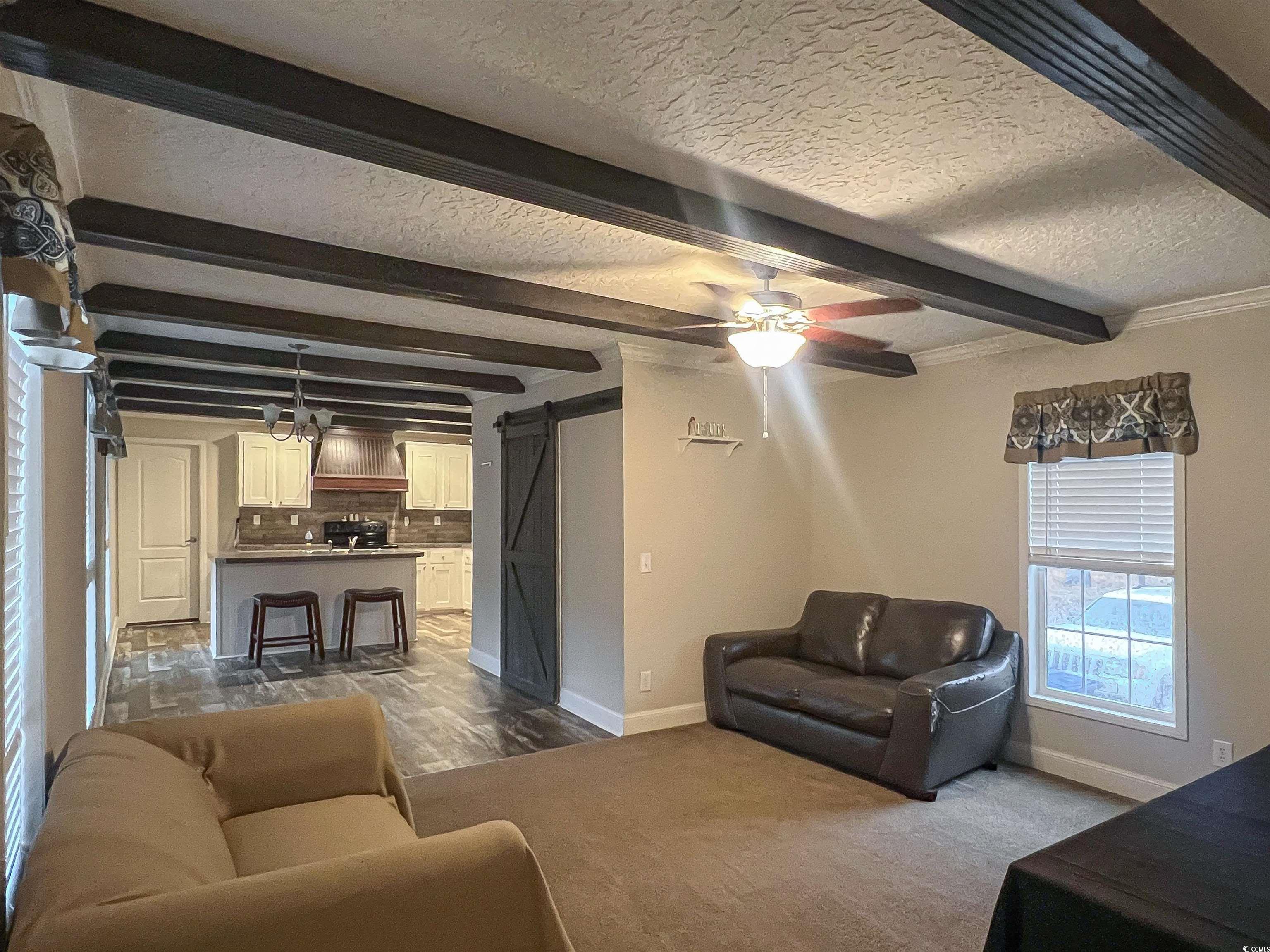 Living room featuring beamed ceiling, a barn door,