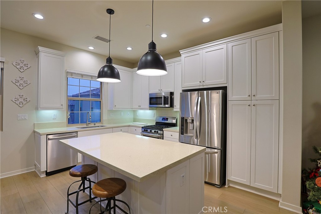78 Kestrel Irvine, CA 92618 - Photo 7 of 32 a kitchen with kitchen island a refrigerator a stove a sink and chairs