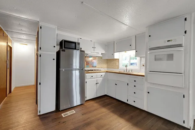 a kitchen with cabinets stainless steel appliances and wooden floor