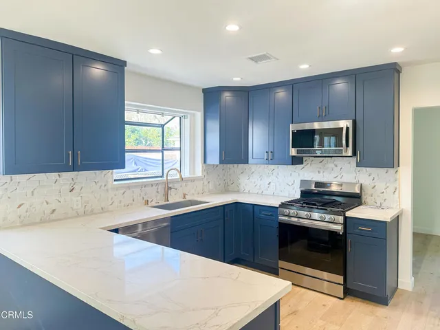 a kitchen with stainless steel appliances a stove sink microwave and cabinets