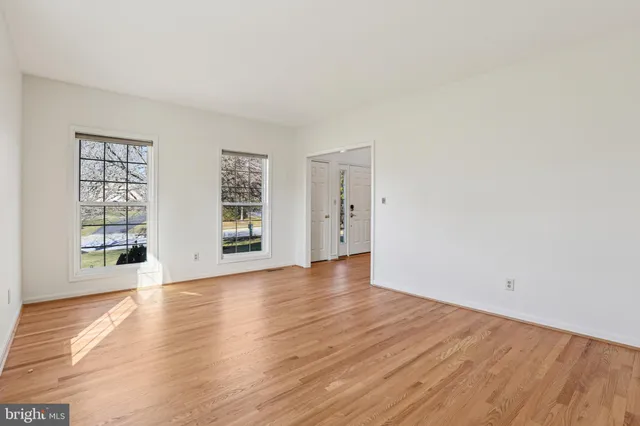 a view of an empty room with wooden floor and windows