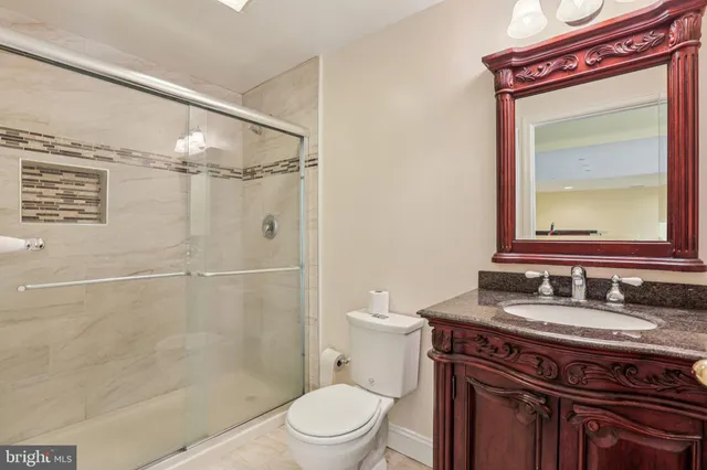 a bathroom with a granite countertop sink toilet a mirror and shower