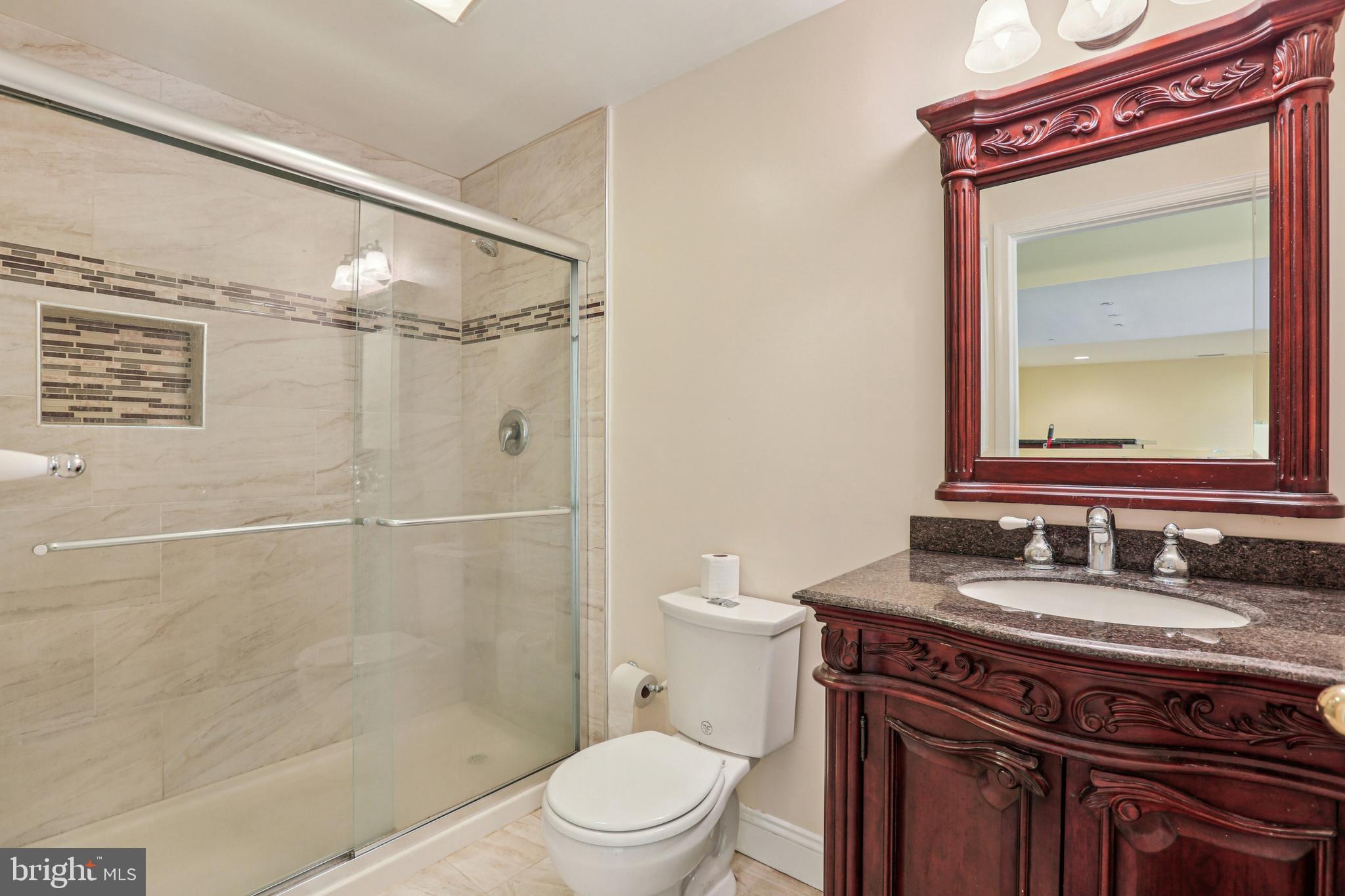 3924 Paul Mill Road Ellicott City, MD 21042 - Photo 37 of 51 a bathroom with a granite countertop sink toilet a mirror and shower