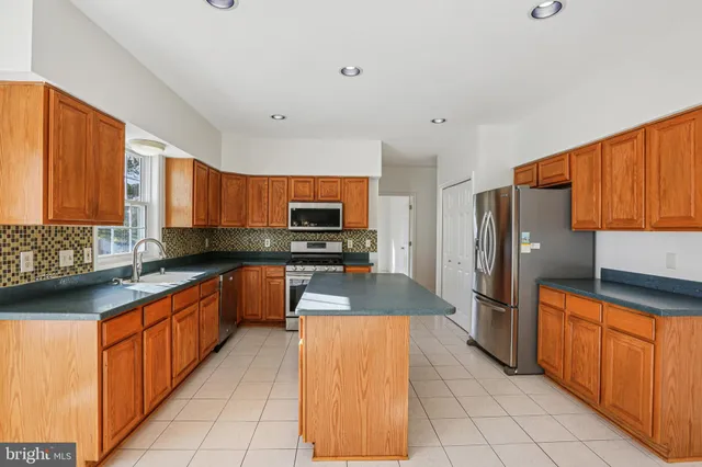 a large kitchen with stainless steel appliances granite countertop a stove a sink dishwasher and a refrigerator