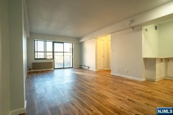a view of an empty room with a window and wooden floor