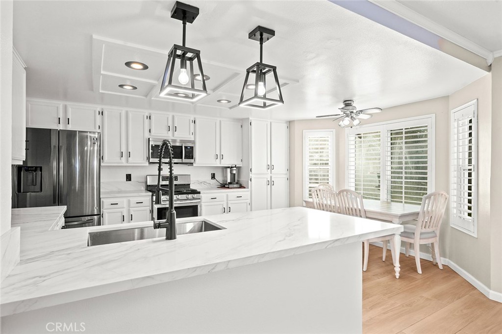1790 North Encina Avenue Rialto, CA 92376 - Photo 14 of 47 a kitchen with stainless steel appliances kitchen island granite countertop a refrigerator a sink dishwasher a dining table and chairs with wooden floor