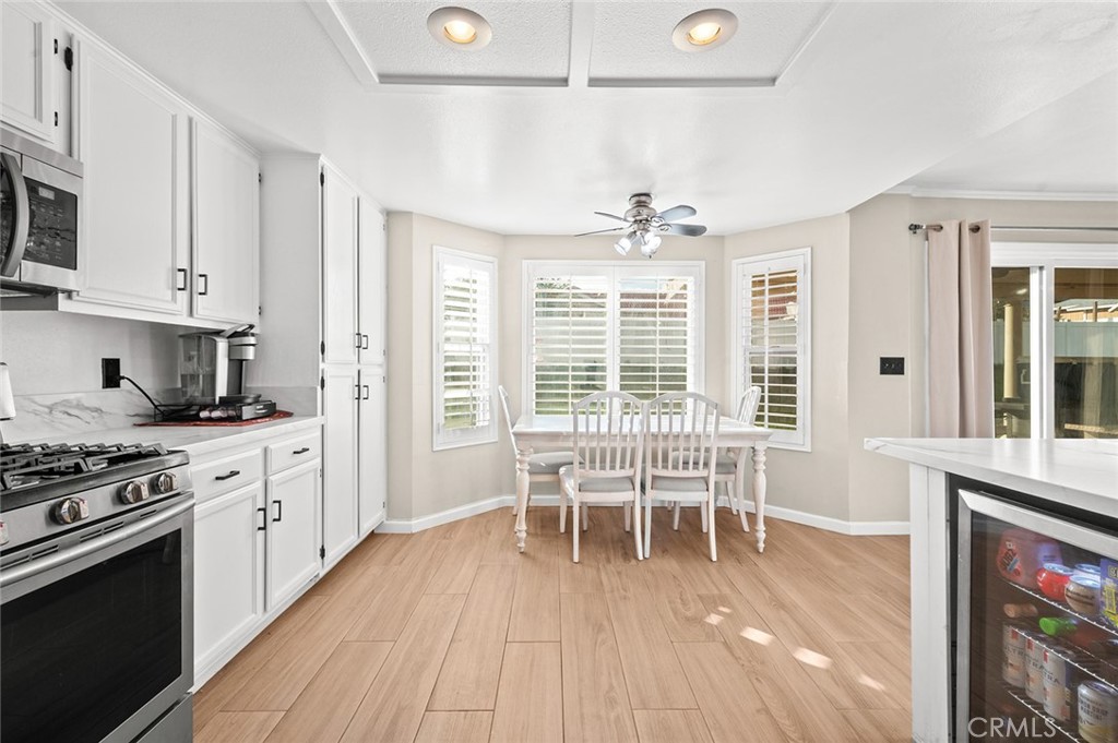 1790 North Encina Avenue Rialto, CA 92376 - Photo 17 of 47 a kitchen with stainless steel appliances a stove a sink dishwasher a dining table and chairs with wooden floor
