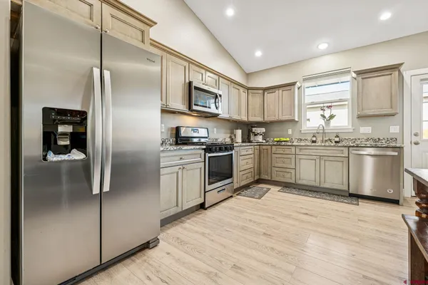 a kitchen with stainless steel appliances granite countertop a refrigerator a sink a stove and cabinets