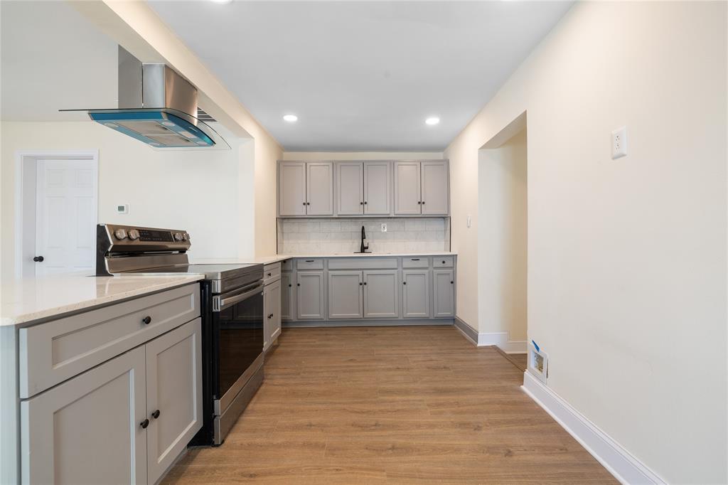 1715 Navaro Street Dallas, TX 75208 - Photo 5 of 33 Kitchen featuring stainless steel range with electric stovetop, gray cabinetry, range hood, light wood-style floors, and light stone counters