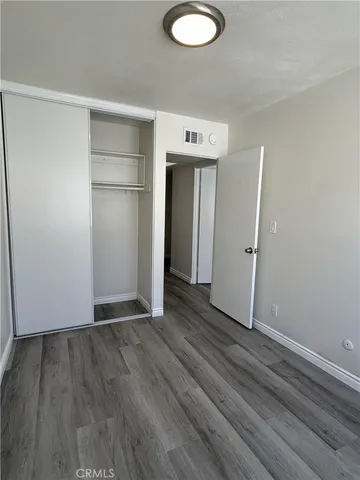 a view of an empty room with wooden floor and closet