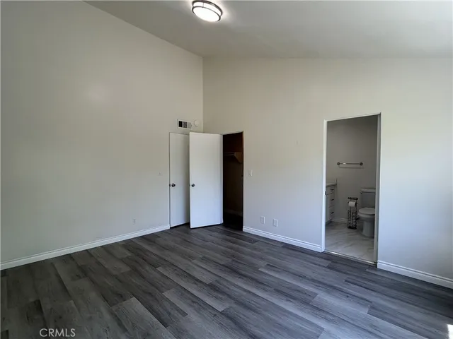 a view of an empty room with wooden floor and closet
