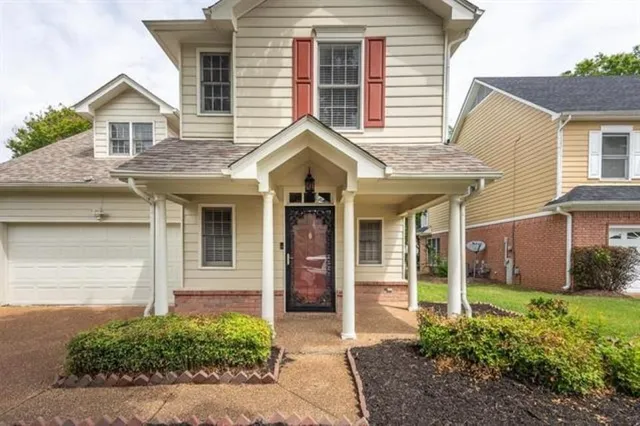 a view of a brick house with large windows and plants