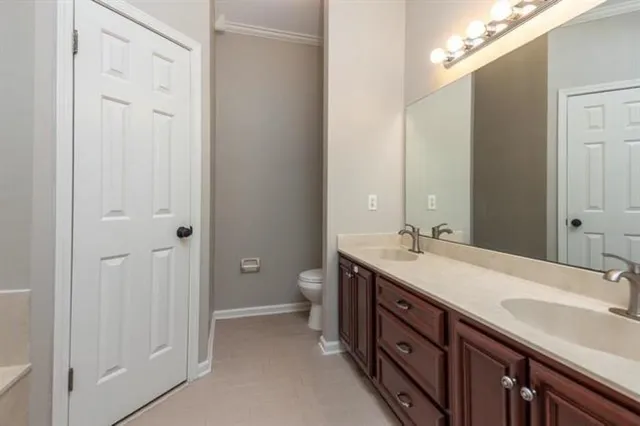 a spacious bathroom with a double vanity sink a toilet and a mirror