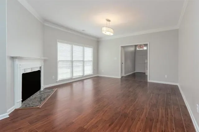 an empty room with wooden floor fireplace and windows