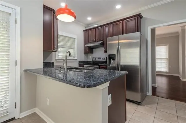 a kitchen with stainless steel appliances granite countertop a sink a refrigerator and a granite counter tops