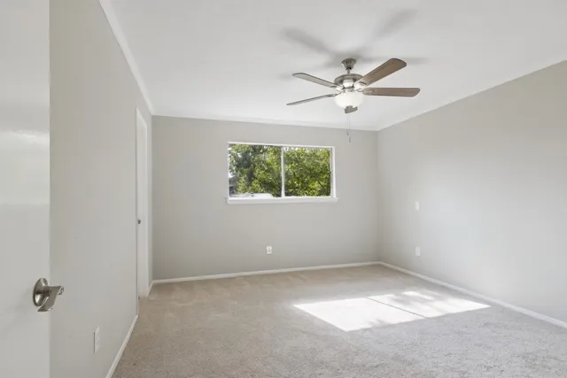 an empty room with a window and a fan